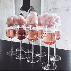 five wine glasses filled with pink liquid and cotton floss in front of a photo