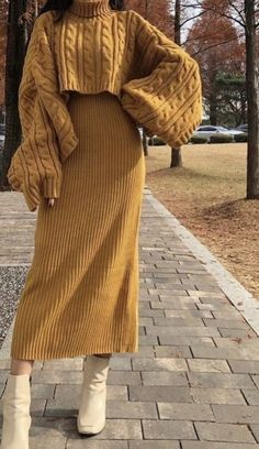 a woman wearing a brown sweater dress and white boots