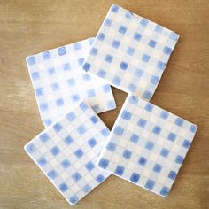 four blue and white checkered tiles sitting on top of a wooden table