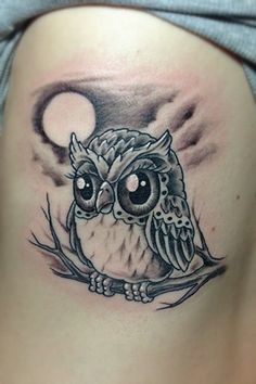 an owl tattoo on the back of a woman's stomach, with a half moon in the background