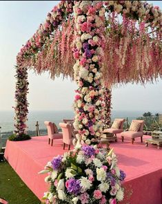 an outdoor wedding setup with pink and white flowers on the table, overlooking the ocean