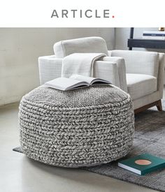 a round ottoman with a book on it in the middle of a living room area