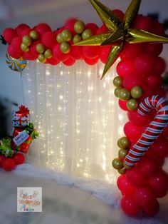 a balloon arch decorated with red and gold balloons, candy canes and star decorations