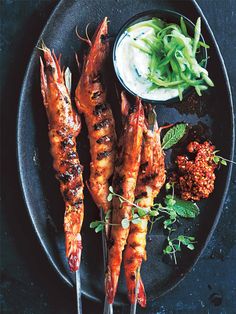 grilled shrimp on skewers with dipping sauce and green beans, garnished with fresh herbs