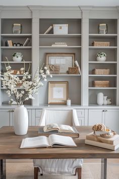 an open book on a wooden table in front of some bookshelves with white flowers