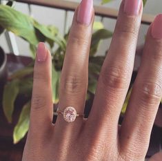 a close up of a person's hand with a ring on their finger and a plant in the background