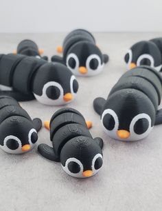 there are many black and white toy penguins on the floor with one penguin looking at the camera