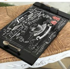 a black and white chalkboard on top of a wicker chair with an ornate design