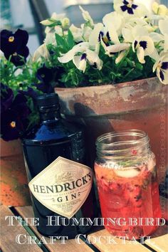 the hummingbird craft cocktail is sitting on a table next to some flowers and bottles