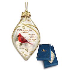 a glass ornament with a cardinal on it and a blue box next to it