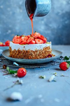 a cake with strawberries on it being drizzled with syrup