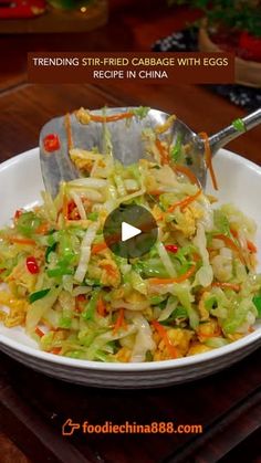 a white bowl filled with coleslaw and carrots next to a metal spoon