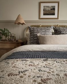 a bedroom with a bed, nightstands and pictures on the wall above it is shown