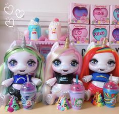 there are three little dolls sitting on the table with cups and toys in front of them