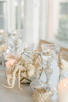 a table topped with lots of white flowers next to candles and vases on top of it