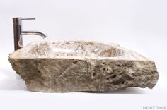 a stone sink sitting on top of a white counter next to a faucet