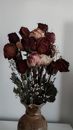 a vase filled with lots of flowers sitting on top of a white table next to a wall