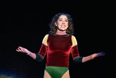 a woman in a bodysuit on stage with her hands out