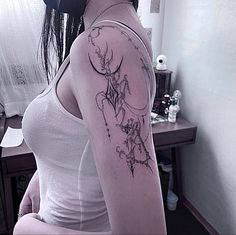 a woman with a flower tattoo on her arm and shoulder is sitting in front of a mirror