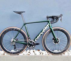 a green bike parked next to a wall with the words cannon on it's front tire