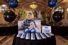 a man sitting on a couch holding a dog in front of a table with balloons