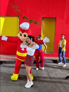 people are standing around in front of a large mascot with a woman hugging her face