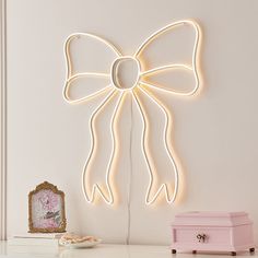 a white bow light hanging on the wall next to a pink chest and small box