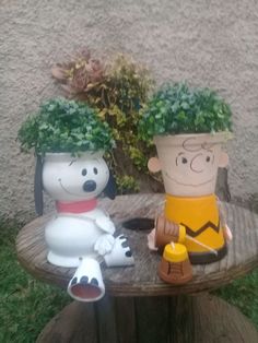 two cartoon figures sitting on top of a wooden table next to a potted plant