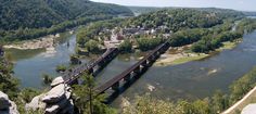 an aerial view of a bridge spanning over a river in the middle of a forested area