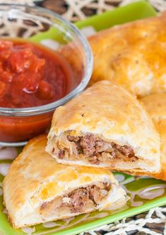 two pastries on a green plate with sauce and ketchup in the background