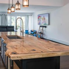 a kitchen with an island made out of wood and lights hanging from it's ceiling