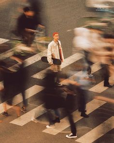 a blurry image of people crossing the street with skateboards in hand and one man holding a skateboard