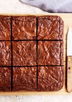 chocolate brownies cut into squares on a cutting board with a knife next to them