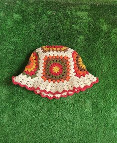 a crocheted hat is laying on the green grass with it's top half open