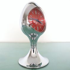 a red clock sitting on top of a metal stand