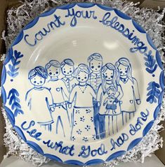 a blue and white plate with an image of people painted on it, surrounded by shredded paper