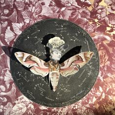 a plate with a painting of a woman's face and moths on the side