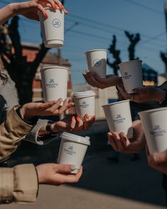 many people are holding up coffee cups in the air and reaching for one cup with their hands