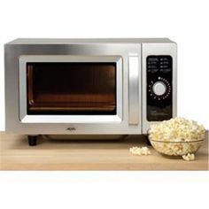 a microwave oven sitting on top of a wooden table next to a bowl of popcorn