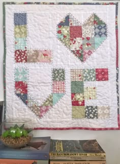 a quilted wall hanging next to some books