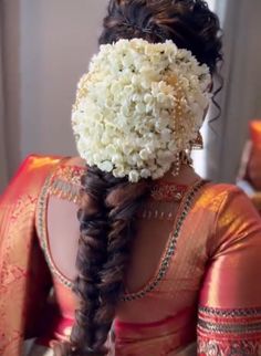 a woman with braids and flowers in her hair is wearing a red sari