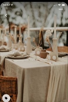 the table is set with white plates and vases