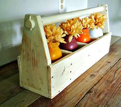 a wooden box filled with vases and flowers on top of a wooden table next to a wall