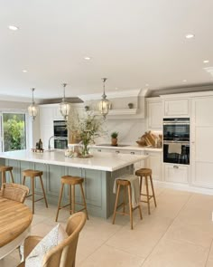 a large kitchen with an island and bar stools next to the stove top oven