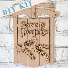 Introducing the Season's Greetings Sled Door Hanger by Janet's Craft Corner, a DIY kit that showcases Season's Greetings alongside a delightful bird, pinecones, and branches set against a light brick background—ideal for elevating your holiday decor. Americana Paint, Snow Sled, Christmas Craft Kit, Wooden Bow, Ice Skate, Cute Signs, Craft Corner, Red Cardinal, Season's Greetings