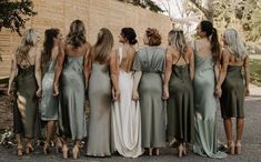 a group of women in dresses standing next to each other on the side of a road