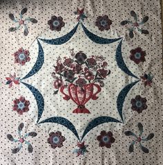 a quilted wall hanging with flowers in the center and an ornate design on it