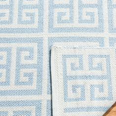 a blue and white rug on top of a wooden floor next to a table with a knife