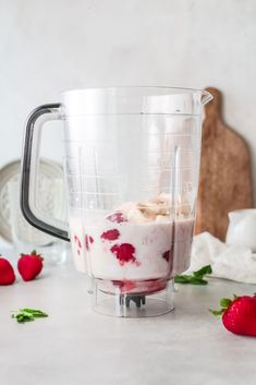 a blender filled with yogurt and strawberries on top of a counter