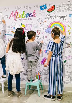 three children drawing on a wall with markers